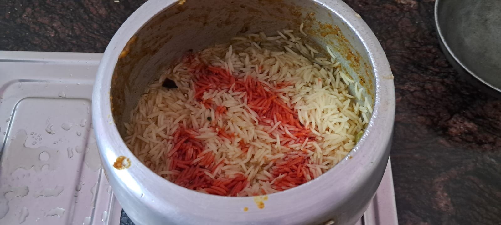 Food coloured rice water added to layered rice before closing lid.